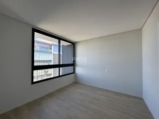 Ambiente interno com piso de madeira e grande janela de vista para a cidade.