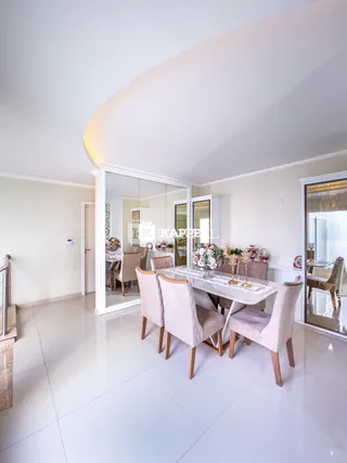 Sala de jantar com mesa de vidro e cadeiras claras em um ambiente bem iluminado.