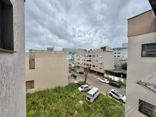 Vista do quintal de uma propriedade em Lajeado, Brasil, com grama alta e veículos estacionados.