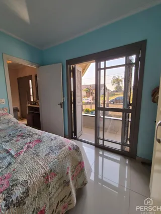 Quarto com cama e porta de vidro que dá acesso ao exterior.