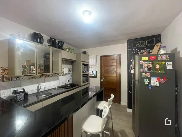 Foto interna de uma cozinha com armários e geladeira.