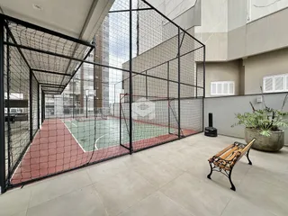 Área externa com quadra esportiva cercada por tela de arame.