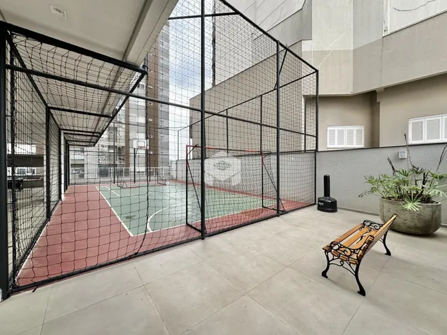Área externa com quadra esportiva cercada por tela de arame.