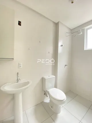Foto do interior de um banheiro com revestimento branco.