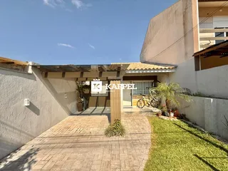 Fachada da casa com calçada e jardim bem cuidado.