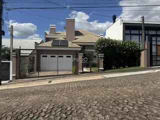 Fachada de uma residência em Lajeado, Brasil, com portão e jardim na frente.
