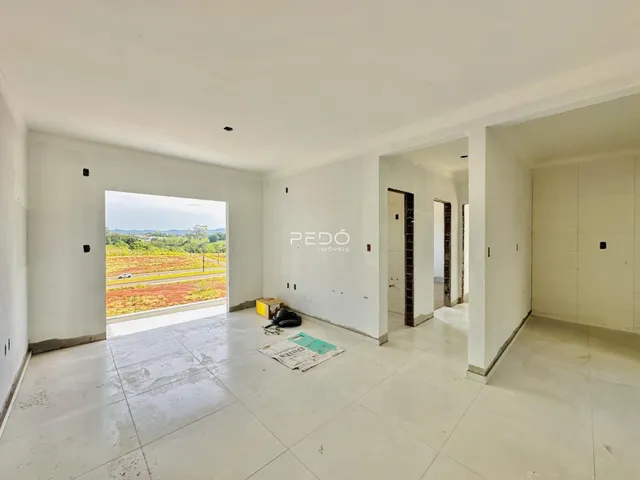 A sala apresenta uma vista aberta para uma área externa de campo.