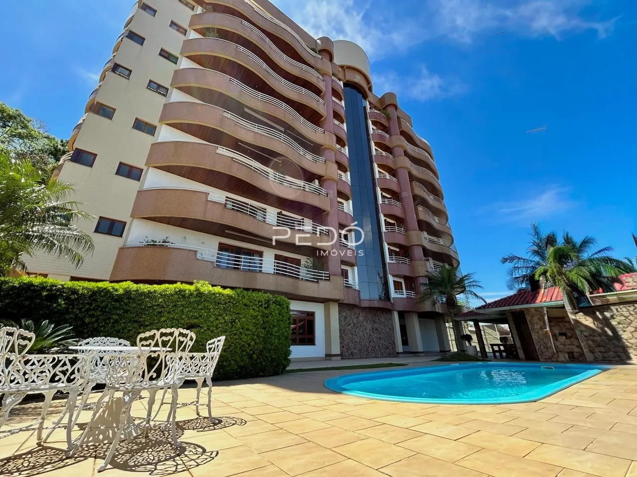 Fachada de um edifício residencial com piscina e área externa em Lajeado, Brasil.