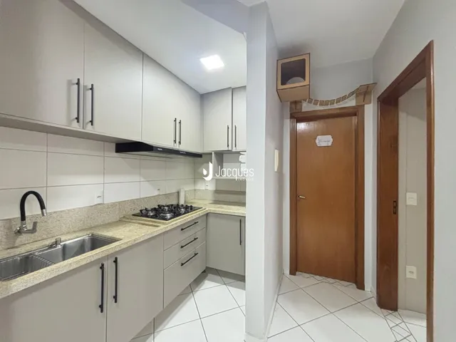 Foto de uma cozinha com armários brancos e bancada clara.