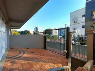 Vista da fachada com piso de tijolos vermelhos e portão de metal.