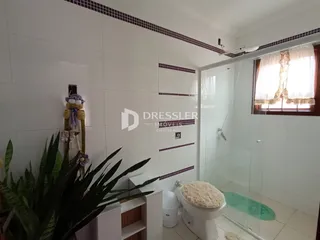 Foto interna de um banheiro com box de vidro e piso cerâmico.