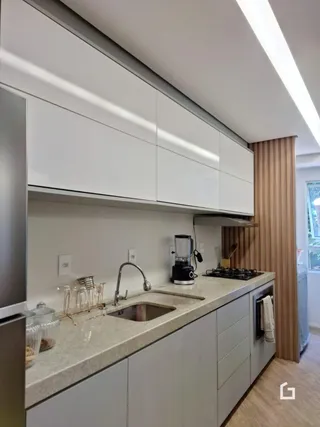 Uma cozinha moderna com armários brancos e bancadas claras.
