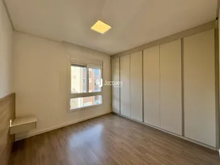 A sala possui piso de madeira e armários embutidos nas paredes.