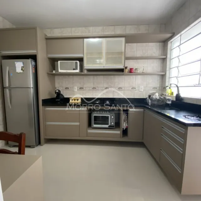 Cozinha com armários em tom neutro e bancada escura.