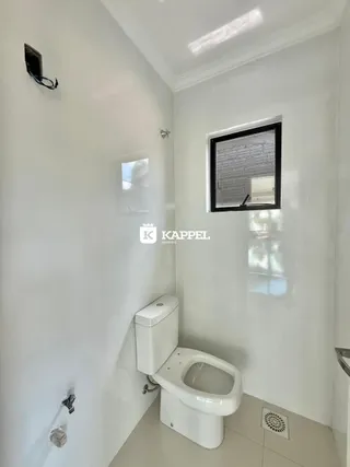 Foto de um banheiro interno com louças brancas e paredes brancas.