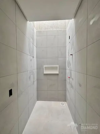 Corredor com paredes revestidas em azulejos cinza claro.
