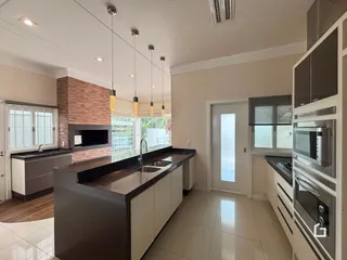 Vista da cozinha moderna com bancada escura e revestimento de tijolo aparente.