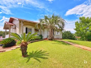 Fachada de uma casa em Lajeado, Brasil com jardim gramado e palmeiras.