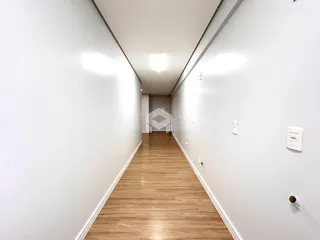 Corredor interno de uma residência com piso de madeira clara.
