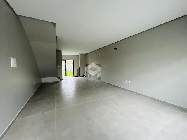 Interior de um espaço amplo com paredes cinzas e piso de concreto.