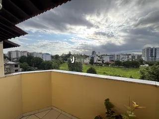 Vista da varanda com paisagem de campos e cidade ao fundo.