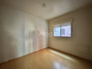 Imagem interna de uma sala com piso de madeira clara e janela.