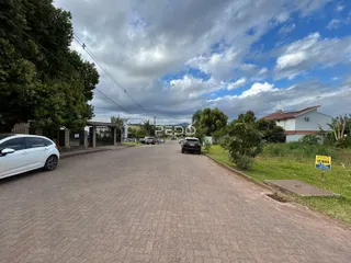 Vista da rua em Lajeado, Brasil, com árvores e residências ao fundo.