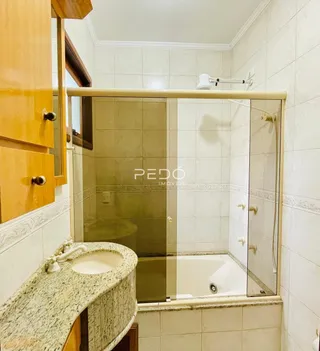 Banheiro com box de vidro e banheira em cerâmica.