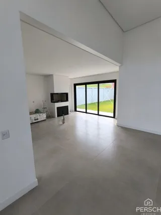 Sala ampla com paredes brancas e porta de vidro voltada para um jardim.