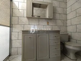 Foto de um banheiro com revestimento de azulejos claros e armário.