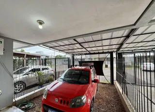 Vista da fachada de uma propriedade com estrutura coberta e cerca de metal.