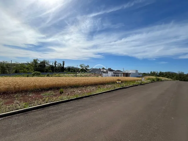 Vista externa de uma propriedade com um campo de cultivo seco e uma estrada no primeiro plano.