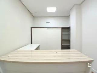 Interior de uma sala com paredes brancas e um balcão de madeira clara.