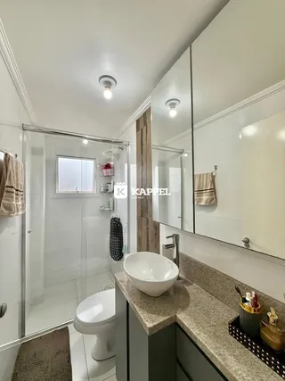 Banheiro moderno com bancada de granito e box de vidro transparente.