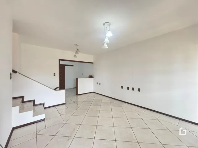 Vista de um corredor interno com escadaria e piso de cerâmica.
