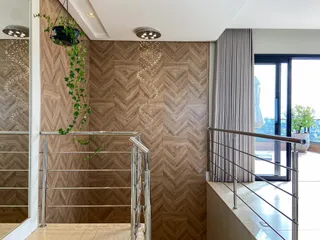 Hall de entrada com revestimento de madeira e grade de metal com vista para a varanda.