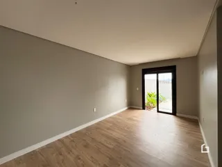 Vista interna de um ambiente com piso de madeira clara.