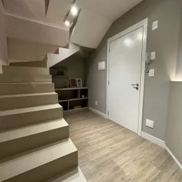 Hall de entrada com escadaria e parede clara.