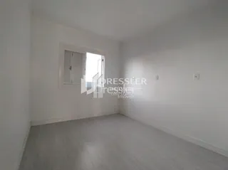 Interior de um cômodo com paredes brancas e porta visível.