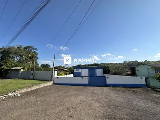 Vista externa de uma propriedade com cerca azul e branca sob um céu azul.