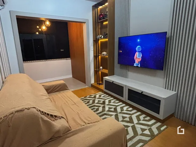Sala de estar com sofá e televisão em um apartamento no Brasil.