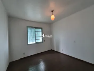 Uma sala de estar com piso de madeira escura e paredes brancas.
