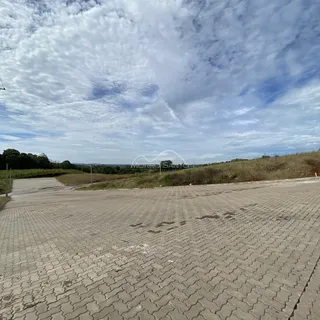 Área pavimentada de acesso com paisagem de campo ao fundo.