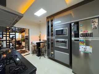 Vista da cozinha moderna com armários escuros e eletrodomésticos em aço inoxidável.