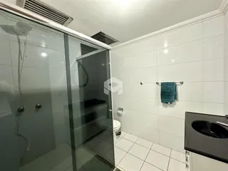A foto mostra o interior de um banheiro com revestimento branco.