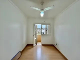 Ambiente interno com piso de madeira e porta de vidro abrindo para o exterior.