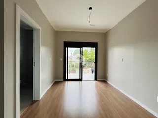 Corredor com piso de madeira e porta de vidro dando acesso ao exterior.