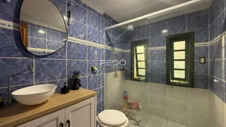 Banheiro com revestimento azul e box de vidro transparente.