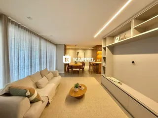 Uma sala de estar com sofá claro e iluminação natural é visível no ambiente.