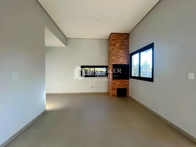 Interior de uma sala com paredes brancas e uma coluna de tijolos aparentes.
